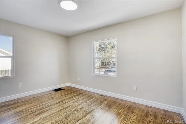 an empty room with wooden floor and windows