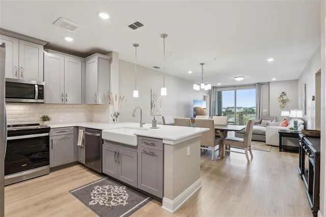 a large white kitchen with lots of counter space a sink appliances and cabinets
