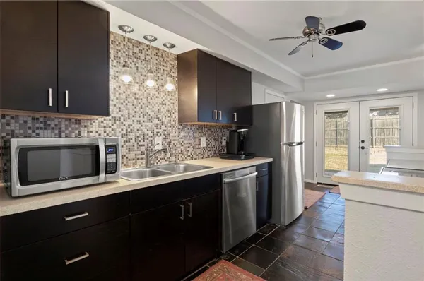 a kitchen with stainless steel appliances kitchen island granite countertop a refrigerator a sink dishwasher a stove and a refrigerator