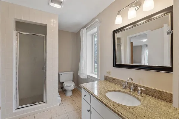 a bathroom with a granite countertop sink toilet and mirror