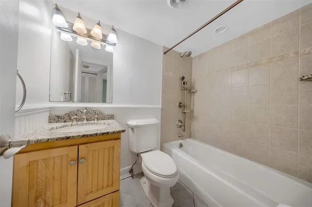 a bathroom with a granite countertop sink a mirror a toilet and bathtub