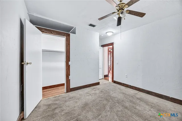 an empty room with closet and a chandelier fan