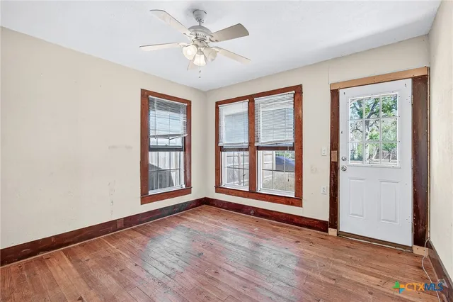a view of an empty room with a window and wooden floor