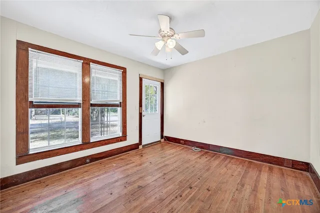 a view of an empty room with wooden floor and a window