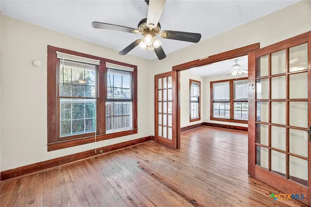 a view of an empty room with wooden floor and a window