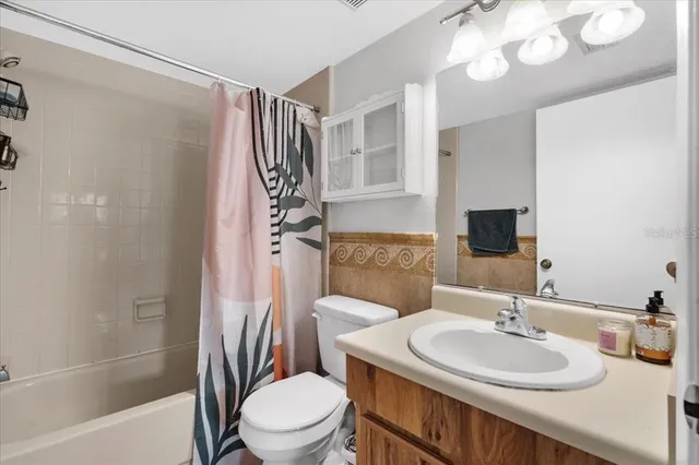 a bathroom with a sink a toilet a mirror a vanity and shower