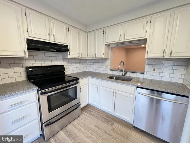 a kitchen with granite countertop wooden cabinets and a stove