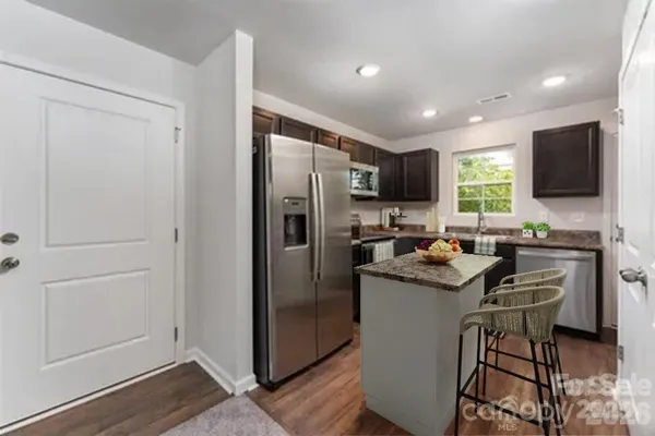 a kitchen with a refrigerator a sink a stove a microwave a dining table and chairs