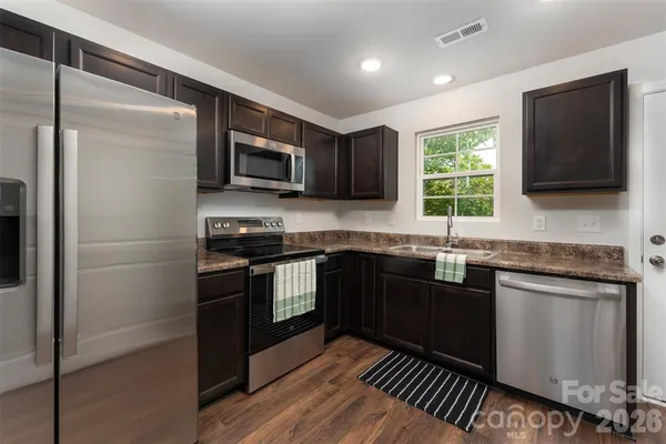 a kitchen with stainless steel appliances granite countertop a stove a sink and a microwave