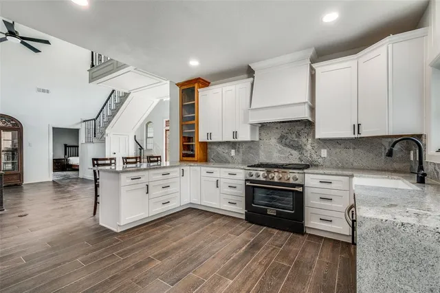 a kitchen with stainless steel appliances granite countertop a stove and white cabinets
