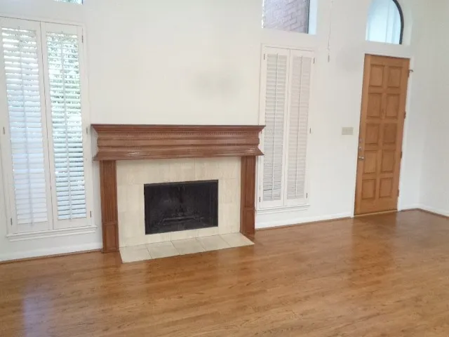 a view of an empty room with wooden floor and a fireplace