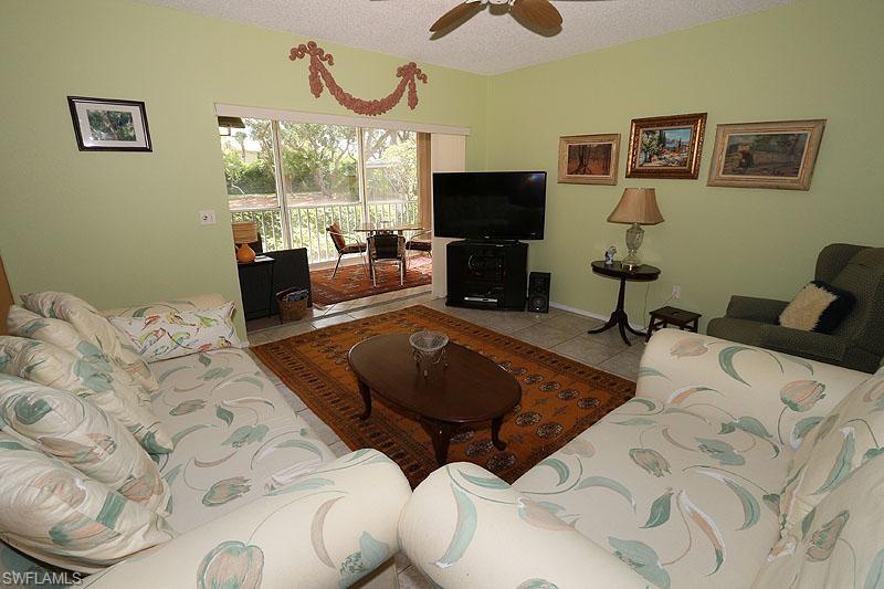 784 Willowbrook Drive, Unit 601 Naples, FL 34108 - Photo 17 of 20 a living room with furniture a flat screen tv and a floor to ceiling window