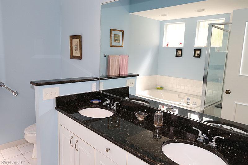 784 Willowbrook Drive, Unit 601 Naples, FL 34108 - Photo 19 of 20 a bathroom with a granite countertop sink a toilet a mirror and vanity