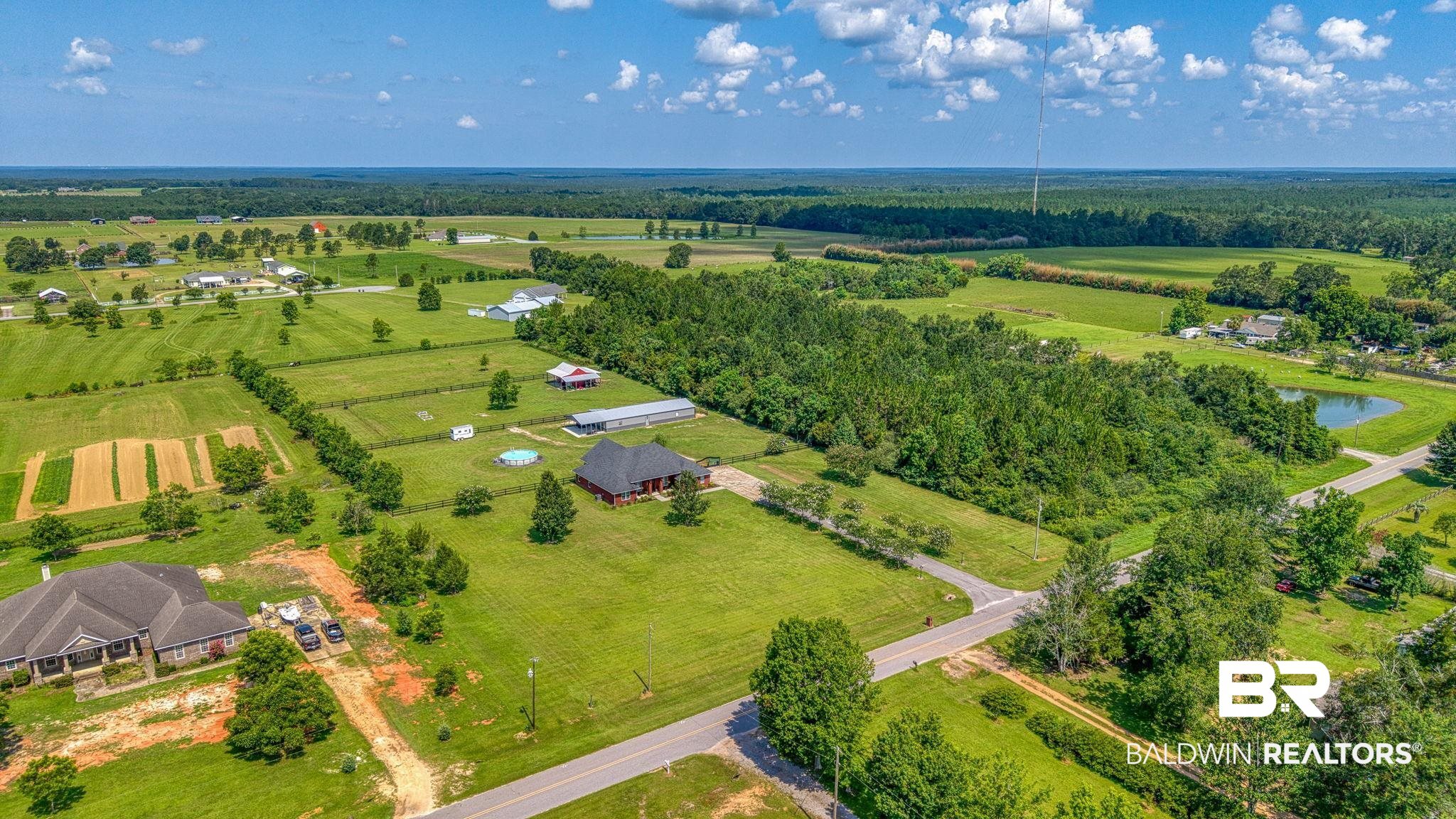 26895 C R Watson Road Robertsdale, AL 36567 - Photo 78 of 89 Expansive acreage featuring a single-story residence with a dark roof, surrounded by mature trees and open fields
