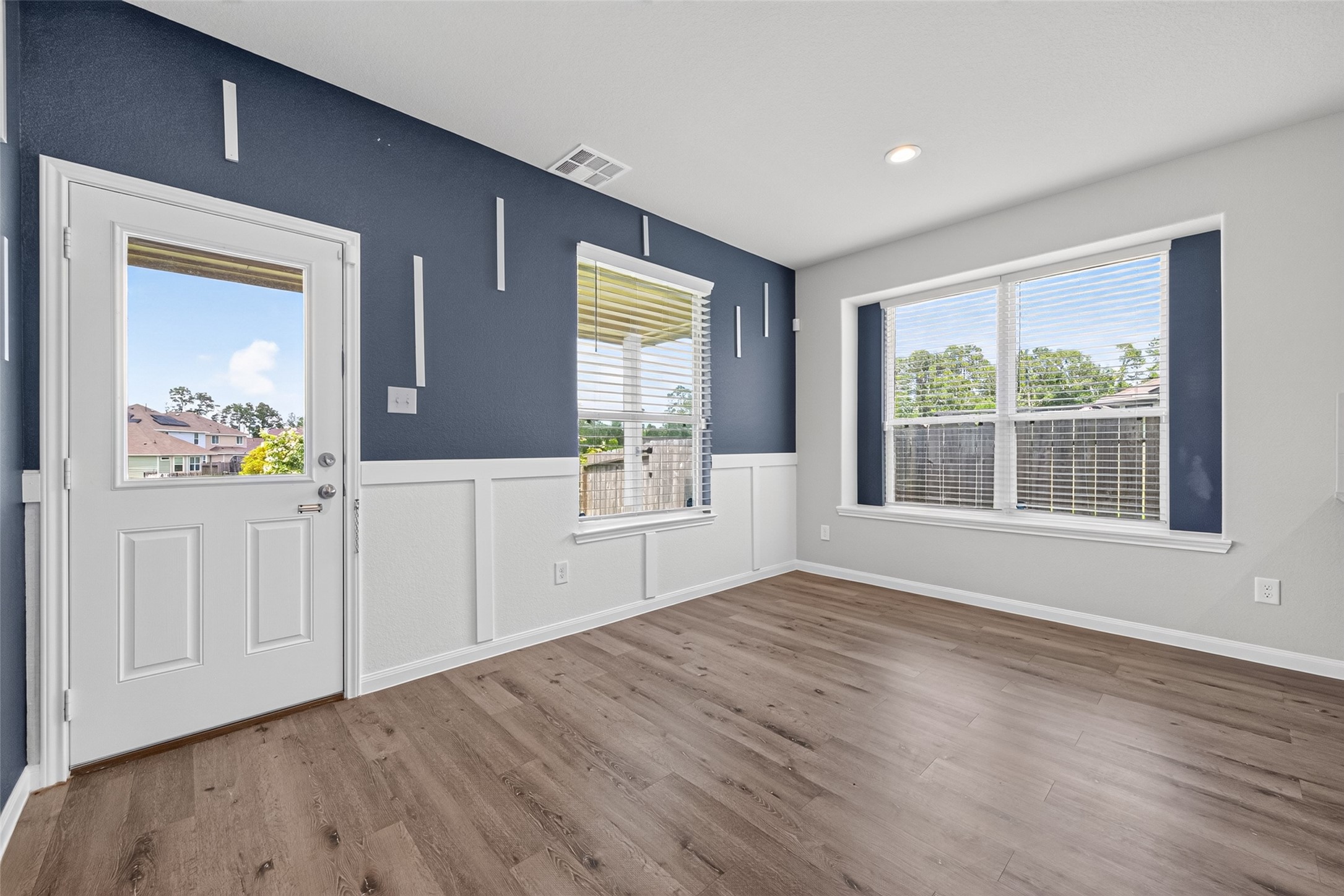 2526 Sturgeon Way Conroe, TX 77384 - Photo 13 of 49 This room features modern flooring, a navy and white color scheme, and ample natural light from large windows. A door provides access to the outside, ideal for easy indoor-outdoor living.