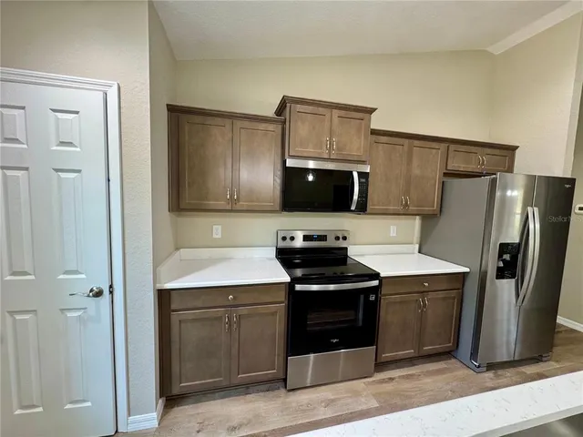 a kitchen with cabinets stainless steel appliances and wooden floor