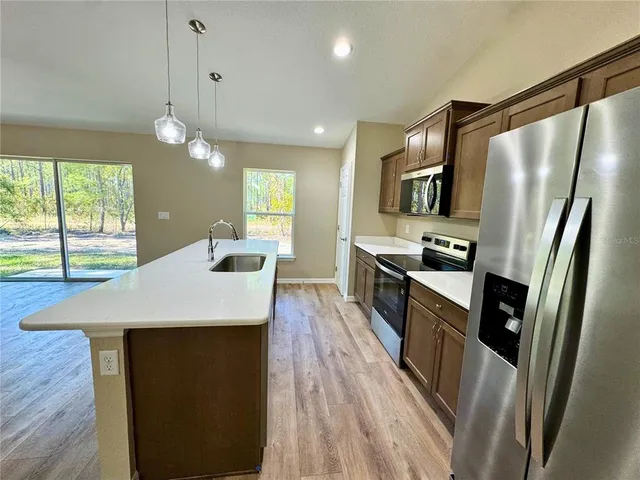 a kitchen with kitchen island a counter top space appliances and a ceiling fan