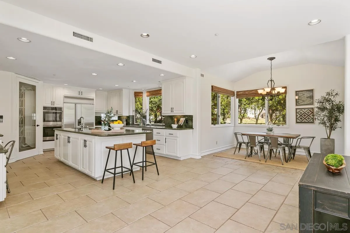 255 Cole Ranch Road Encinitas, CA 92024 - Photo 15 of 45 a kitchen with stainless steel appliances kitchen island granite countertop a table and chairs in it