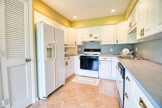 a kitchen with stainless steel appliances granite countertop a stove a sink and a refrigerator