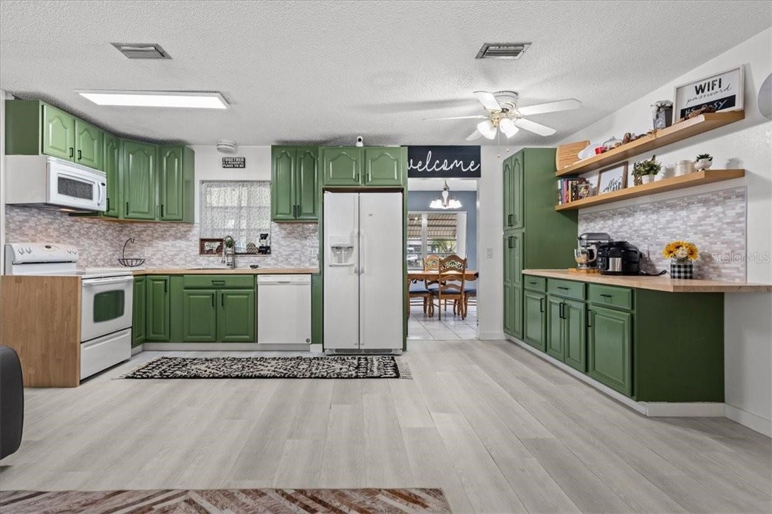424 Wisconsin Avenue St. Cloud, FL 34769 - Photo 12 of 36 a kitchen with stainless steel appliances a stove a refrigerator a sink dishwasher and a dining table with wooden floor