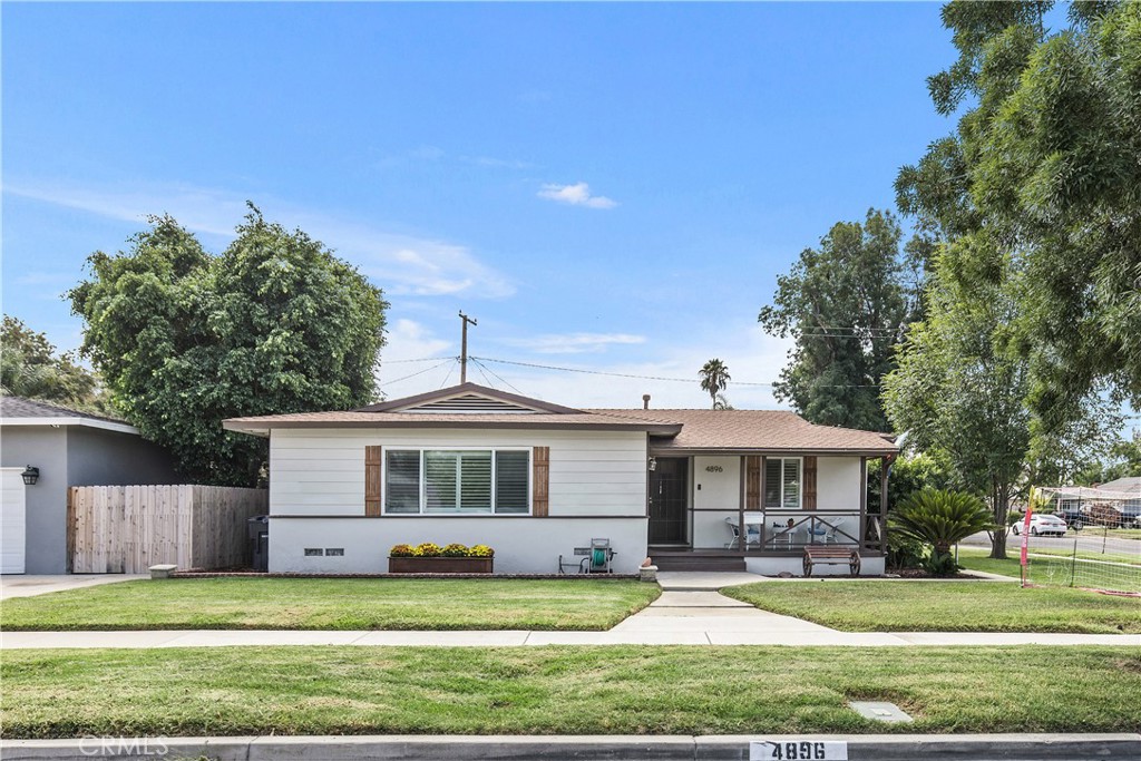 a front view of a house with a garden and trees