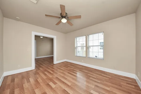 an empty room with wooden floor fan and windows