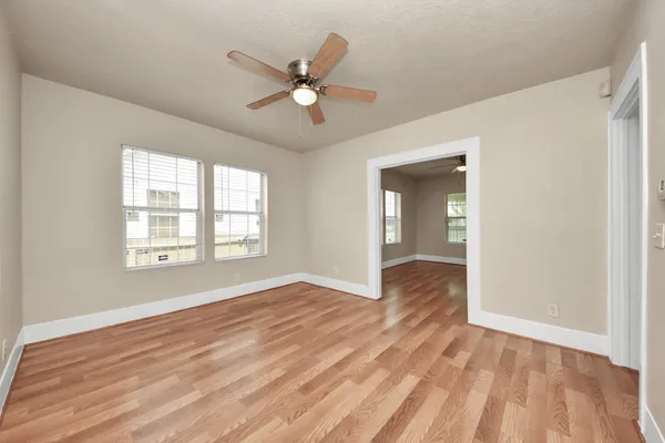 a view of an empty room with wooden floor and a window