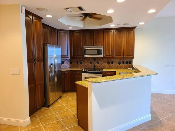 a kitchen with kitchen island granite countertop wooden cabinets a refrigerator and a sink