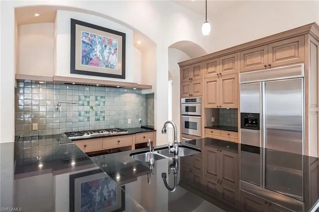 a kitchen with stainless steel appliances granite countertop a sink a stove and a wooden floors