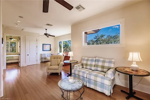 a living room with couches a large dining table and with potted plants