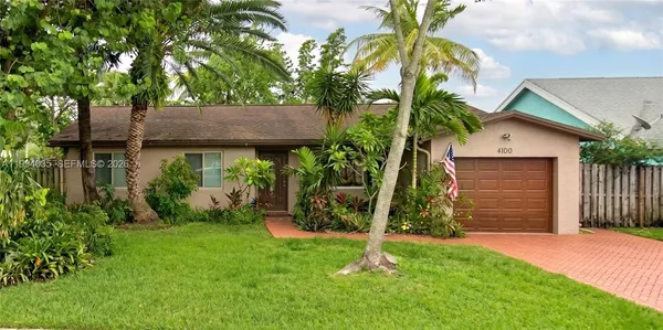 a backyard of a house with plants and palm tree