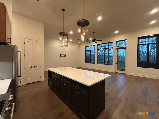 a large kitchen with stainless steel appliances granite countertop a refrigerator a oven and a wooden floors