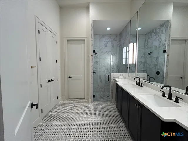 a bathroom with a double vanity sink a large mirror a shower and a bathtub