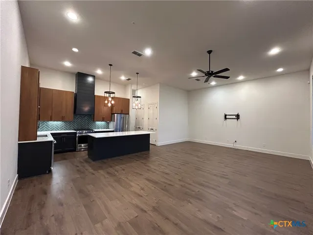 a large kitchen with a sink and dishwasher a stove top oven with wooden floor