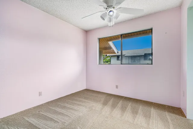 an empty room with a window and a ceiling fan