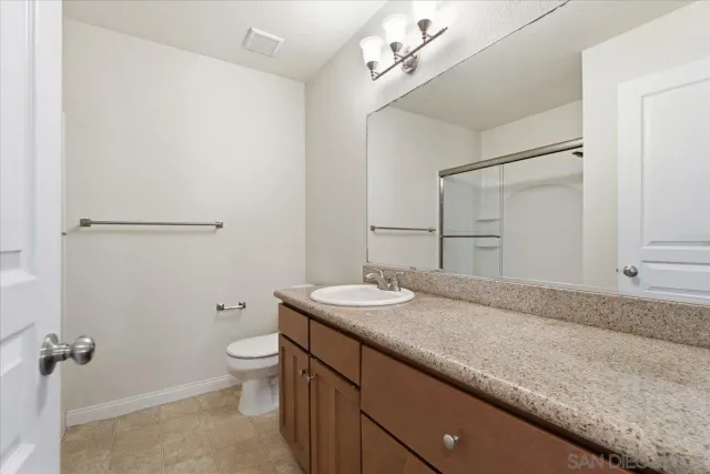 a bathroom with a granite countertop sink mirror and toilet