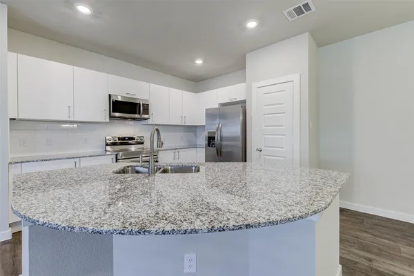 a kitchen with stainless steel appliances granite countertop a sink a stove and a wooden floors