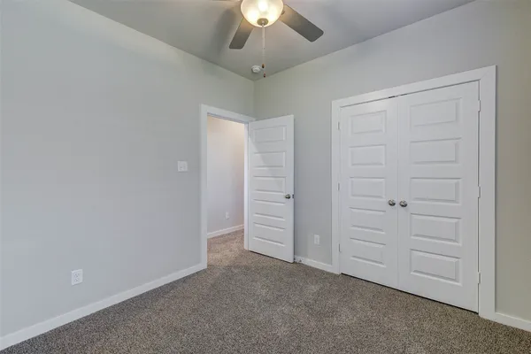 an empty room with chandelier fan and windows