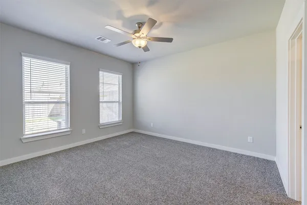 an empty room with a chandelier fan and windows