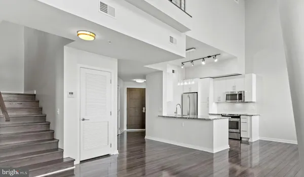 an empty room with wooden floor and a kitchen