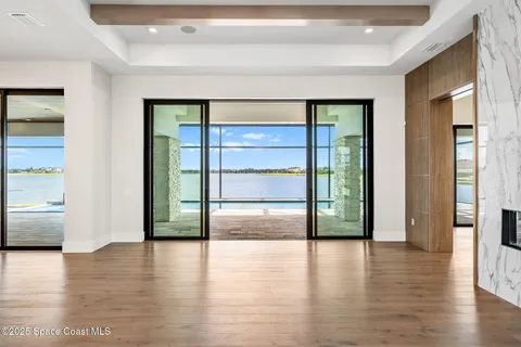 a view of an empty room with window and wooden floor