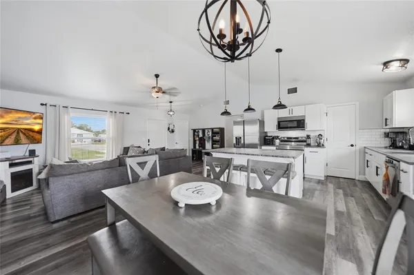 a view of a dining room with furniture a kitchen and chandelier