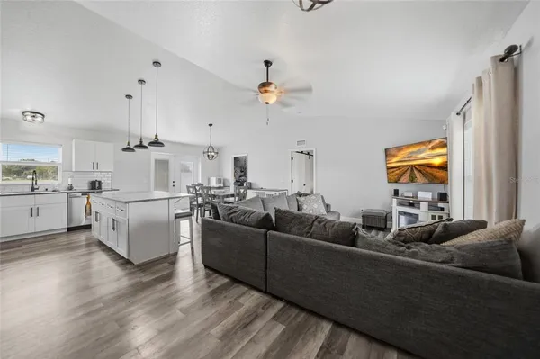 a living room with furniture kitchen view and a chandelier