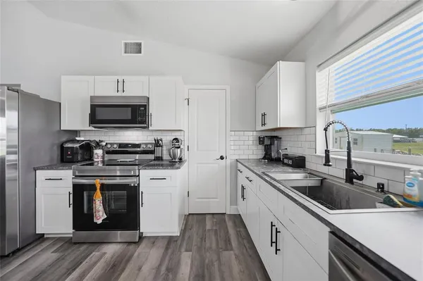 a kitchen with cabinets stainless steel appliances a sink dishwasher a stove and a refrigerator