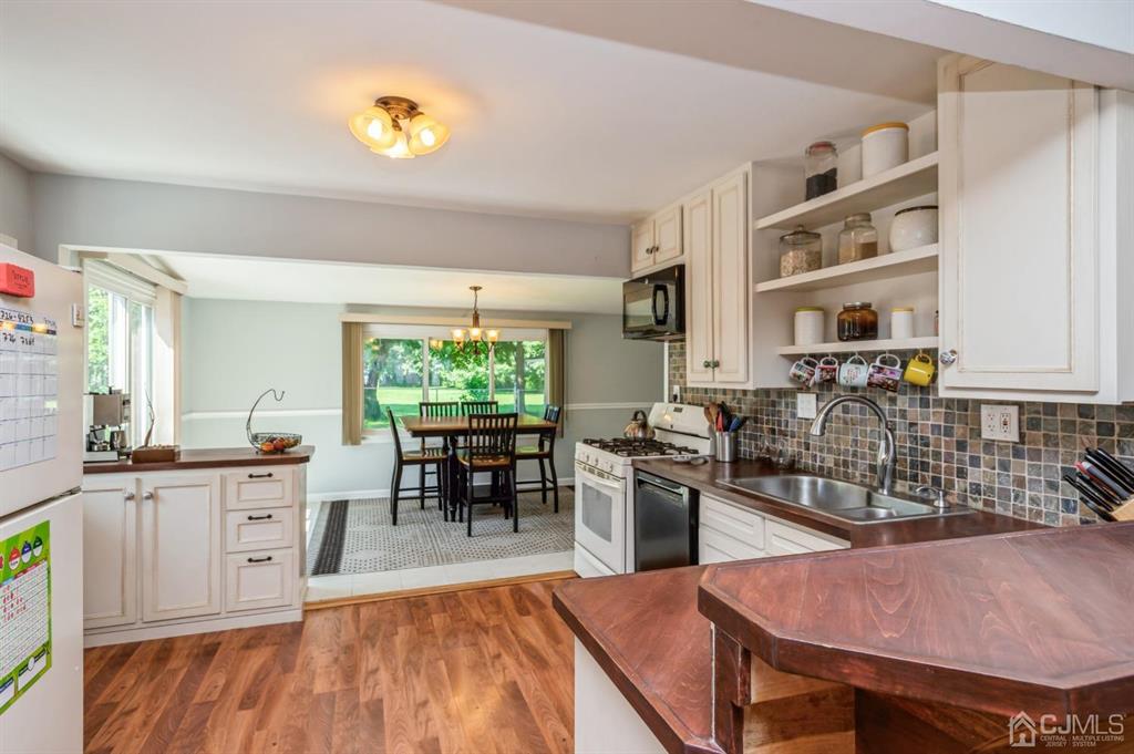 24 Markham Road Edison, NJ 08817 - Photo 5 of 20 a kitchen with stainless steel appliances granite countertop a stove top oven a sink a dining table and chairs with wooden floor