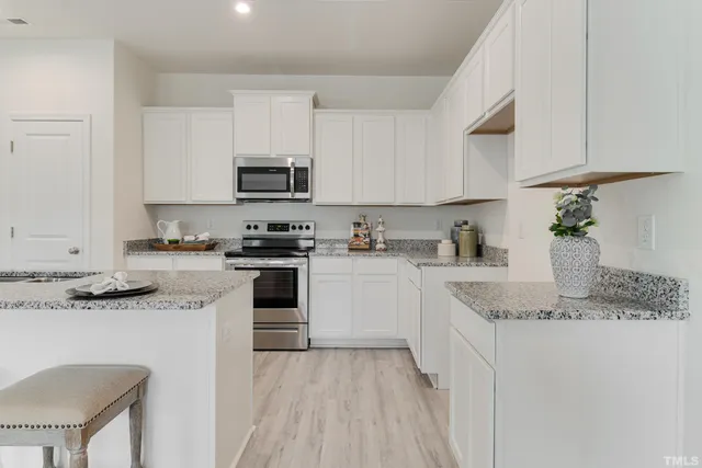 a kitchen with granite countertop a sink stove and white cabinets