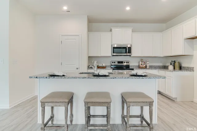a kitchen with granite countertop white cabinets and stainless steel appliances