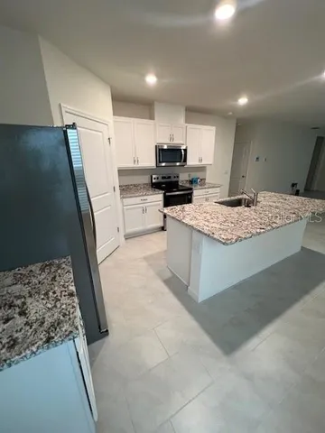 a large kitchen with a stove a refrigerator and a sink