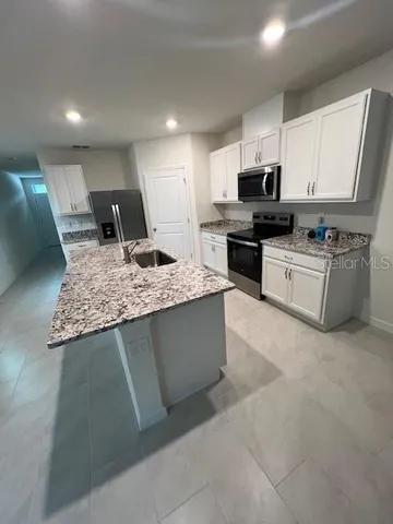 a kitchen with stainless steel appliances granite countertop a sink dishwasher stove and refrigerator