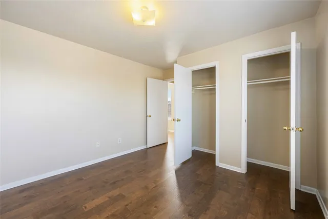 an empty room with wooden floor & closet area
